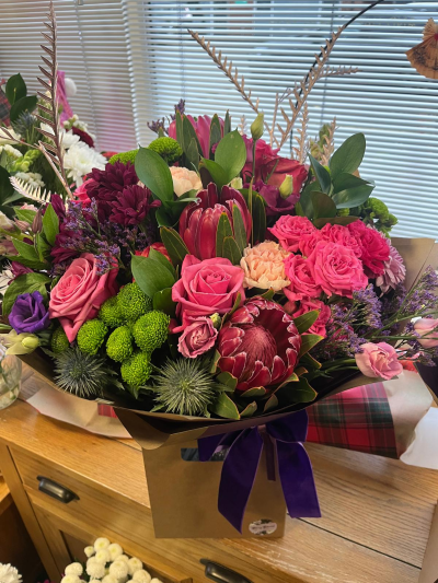 Ruby Velvet Luxury - A striking hand-tied arrangement showcasing rich berry, blush and deep plum tones, beautifully complemented by fresh greenery and unique textural accents. Designed to make a lasting impression, this luxurious bouquet blends bold colour, elegant form and contemporary styling for a sophisticated display. Presented in a stylish gift bag and finished with a sumptuous ribbon, it is an ideal choice for milestone celebrations, special occasions, heartfelt gifts or whenever you want to send something truly unforgettable.