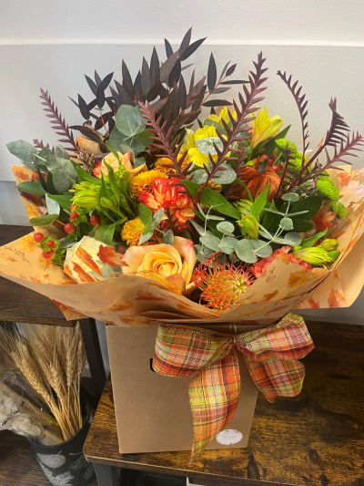 Harvest Charm - Inspired by the rich colours and textures of the changing seasons, this stunning arrangement brings together warm amber, golden apricot, copper and deep burgundy tones in a beautifully layered design. Accented with seasonal foliage, berries and unique textural elements, it captures the cosy elegance of an autumn countryside walk. Presented in a stylish gift bag with coordinating autumn-themed wrapping and a rustic tartan bow, this arrangement is perfect for birthdays, thank-you gifts, celebrations or adding a touch of seasonal warmth to any home.