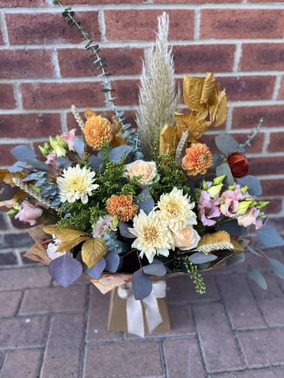 Autumn Harvest - Autumnal foliage and dried grasses amongst seasonal Dalia’s and chrysanthemums with complementary flowers like lisianthus and fillers in peachy orange tones for a soft autumnal feeling. Wrapped in Kraft paper with autumn leaf print.